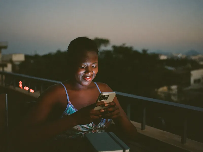 Une femme consulte ses objectifs d'épargne sur son téléphone, le soir.